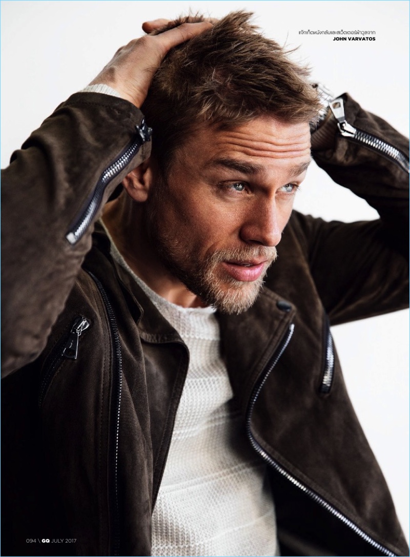 Delivering a side profile, Charlie Hunnam wears a suede biker jacket with a sweater from John Varvatos.