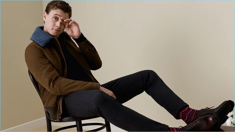 Ready for fall, George MacKay wears a Prada shearling-trimmed shell flight jacket $1,920. He also sports a Prada zip-detailed sweater $850, trousers $660, and leather oxford shoes $720.