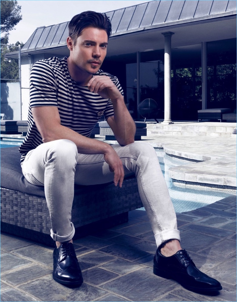 Relaxing outdoors, Josh Henderson wears a striped tee by The Kooples with AllSaints jeans, and Joseph Abboud dress shoes.