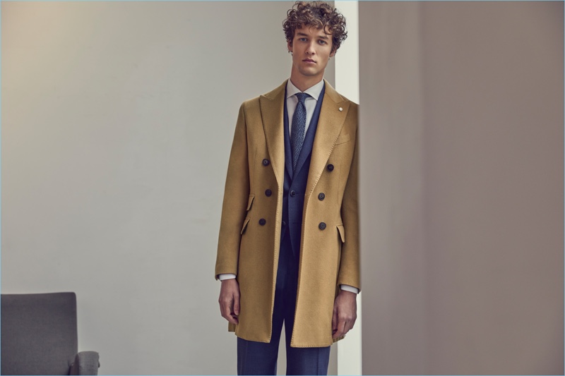 Model Marçal Taberner dons a double-breasted camel coat with a suit from Luigi Bianchi Mantova's fall-winter 2017 collection.