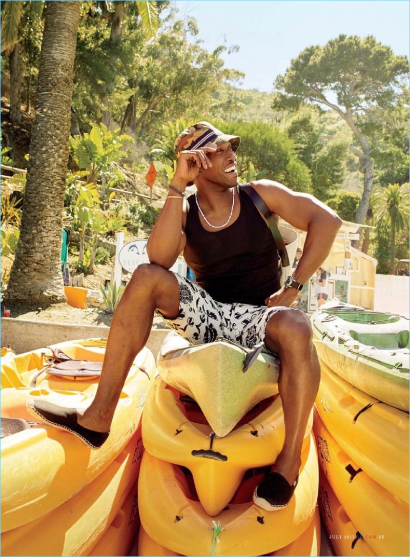 Stealing a moment to relax, Mahershala Ali wears an Emporio Armani tank, Junya Watanabe shorts, and a Moncler hat.