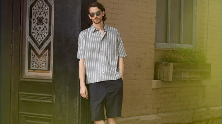 A summer vision, Jeremy Young wears a Vince stripe short-sleeve shirt $225, shorts $285, and slide sandals $95 with Paul Smith sunglasses $310.