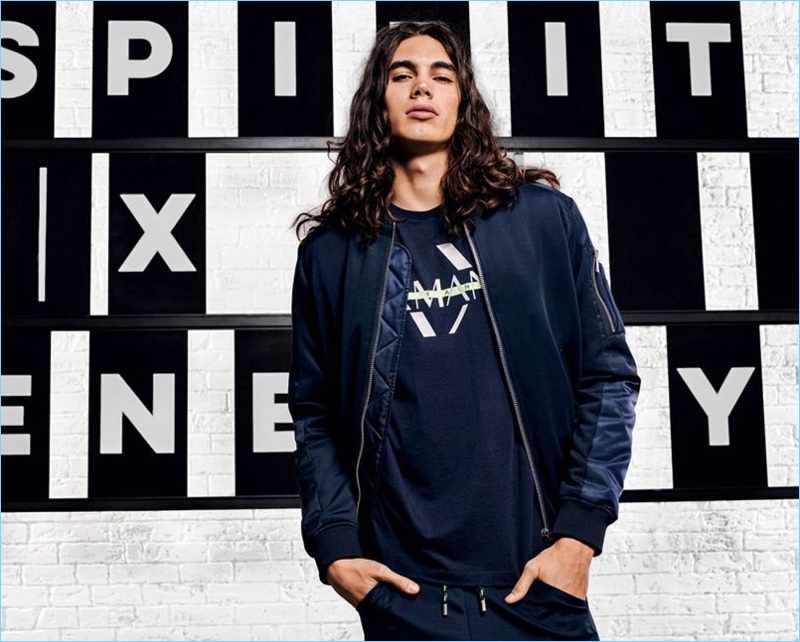 Vito Basso is a cool vision in a bomber jacket, graphic tee, and pants from Armani Exchange.