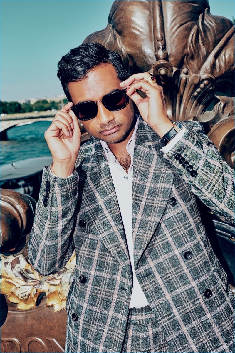 Actor Aziz Ansari wears a Gucci suit with a Berluti shirt. He also sports a Rolex watch and Saint Laurent sunglasses.