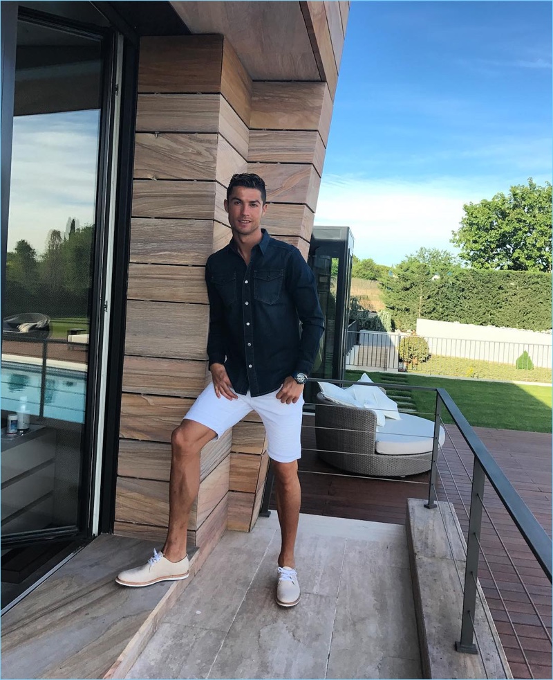 Enjoying a warm day, Cristiano Ronaldo doubles down on denim with a dark wash shirt and CR7 shorts.