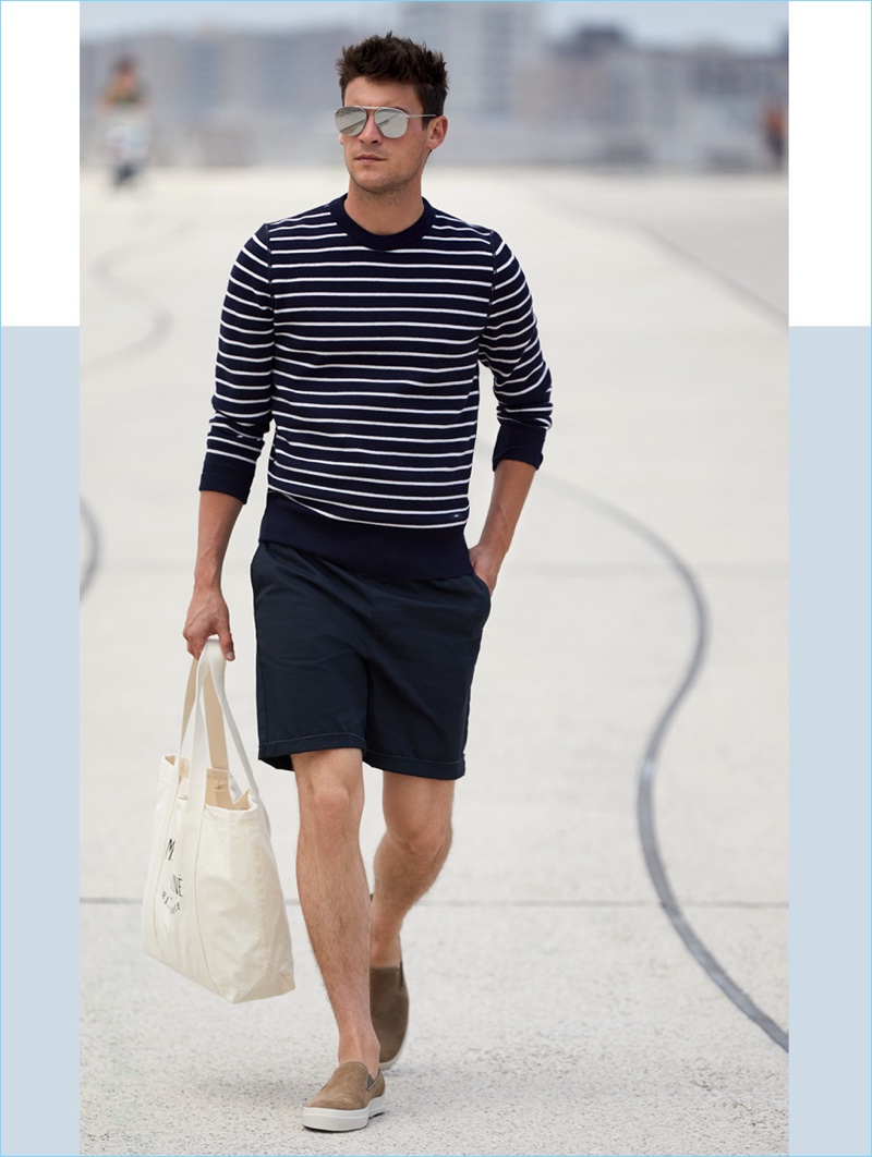 East Dane makes a case for shorts and knitwear. Embracing navy, Miles Garber wears an AMI striped sweater $200 with RVCA shorts $45. He also sports Vince suede slip-on sneakers $157.50, a Maison Kitsune tote bag $80, and Le Specs sunglasses $89.