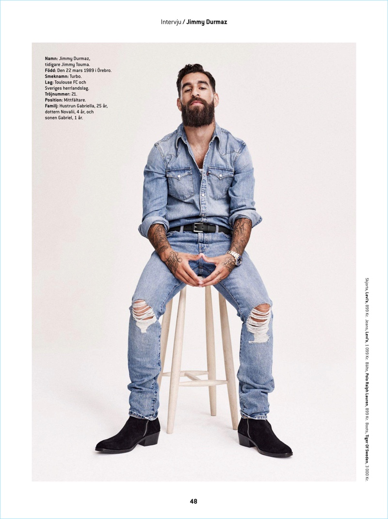 Sitting for a portrait, Jimmy Durmaz wears a denim shirt and jeans by Levi's. He also sports a POLO Ralph Lauren belt and Tiger of Sweden boots.