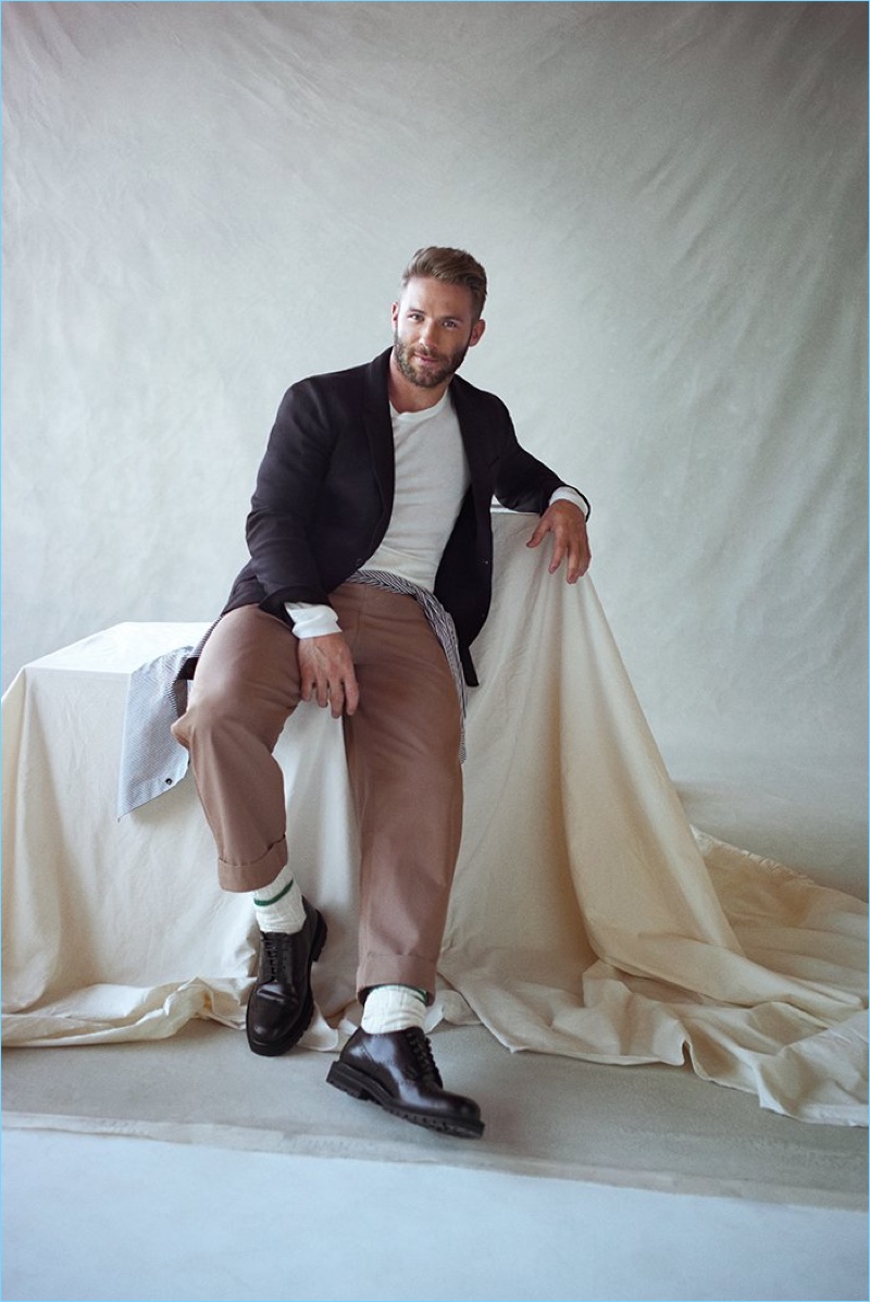 Posing for a studio portrait, Julian Edelman wears an AMI blazer, Dries Van Noten shirt, and P.Johnson sweater. He also sports Dries Van Noten wingtip brogues and Craig Green wide-leg trousers.