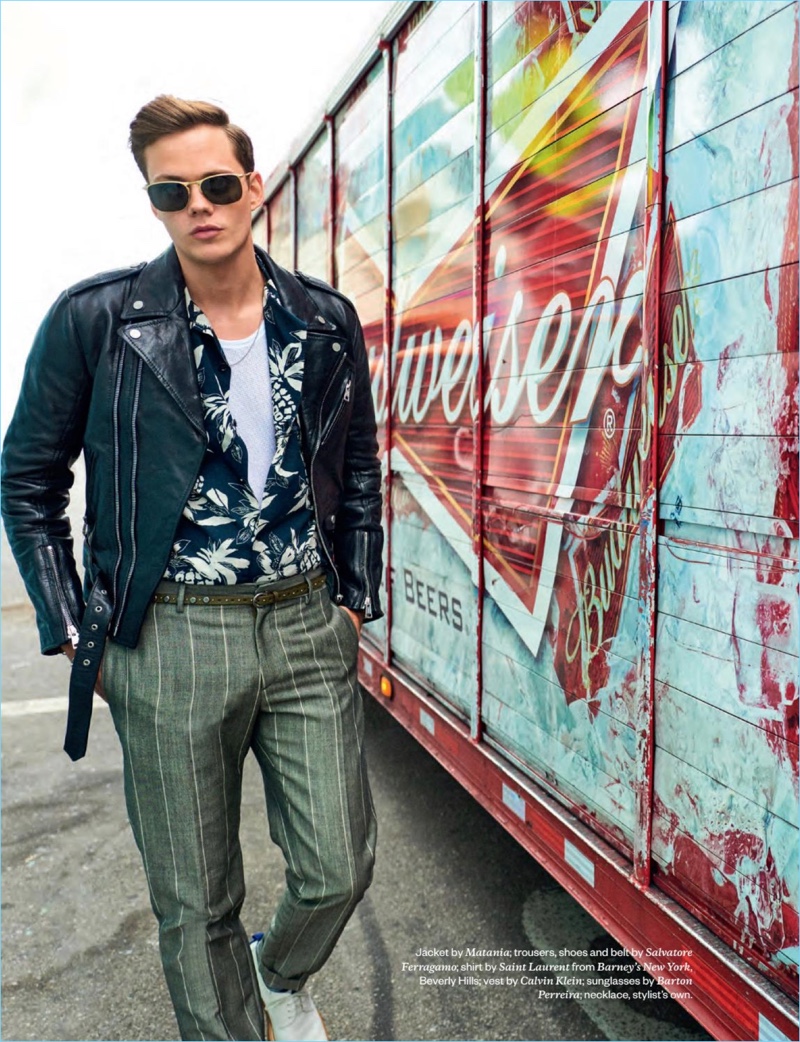 A cool vision, Bill Skarsgård wears a Matania leather biker jacket with a Saint Laurent shirt. Skarsgård also sports a Calvin Klein tank and Barton Perreira sunglasses with trousers and accessories by Salvatore Ferragamo.