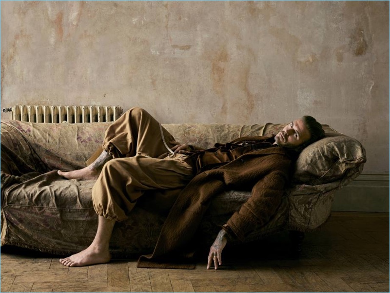 Relaxing, David Beckham wears a Joseph coat with an Etro silk velvet blazer, Kolor shirt, and Vivienne Westwood pants.