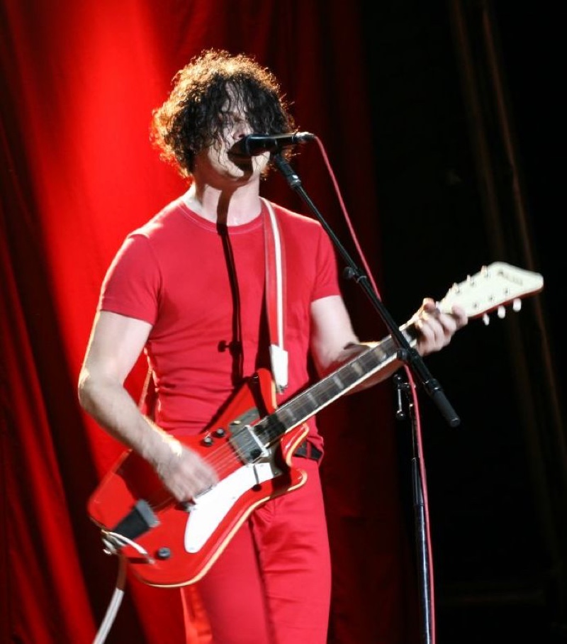 Jack White of The White Stripes wears a red outfit while performing.