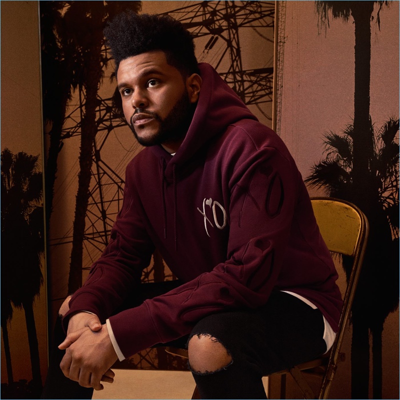 The Weeknd wears an embroidered purple hoodie $34.99 with ripped denim jeans.