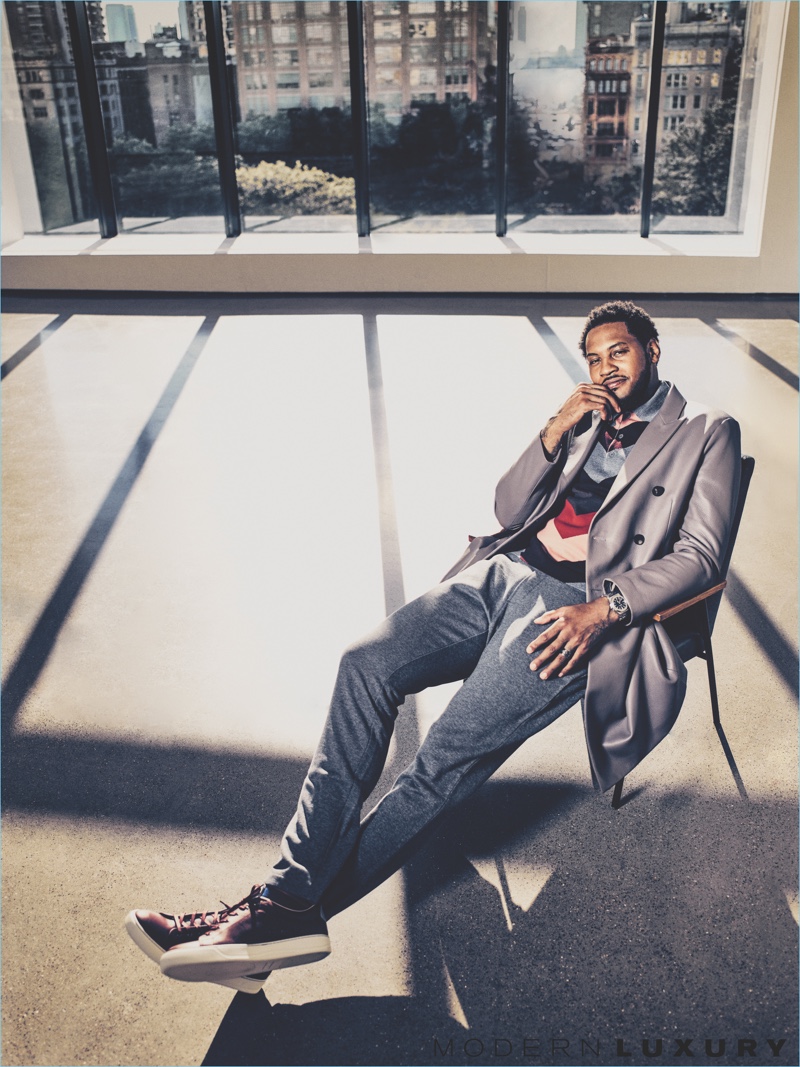 Relaxing, Carmelo Anthony wears a coat, knit, and trousers from Bottega Veneta. Anthony's look is complete with Lanvin sneakers.