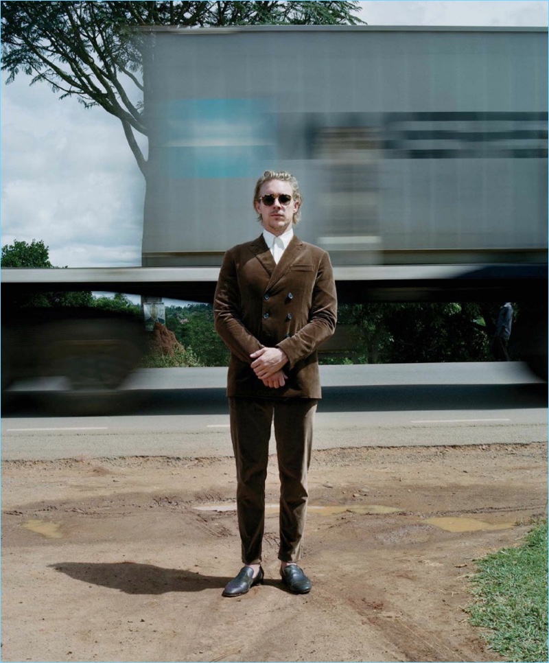 Diplo wears a double-breasted Berluti suit in brown. A Jeffrey Rüdes shirt, Christian Louboutin shoes, and Mykita sunglasses complete his look.