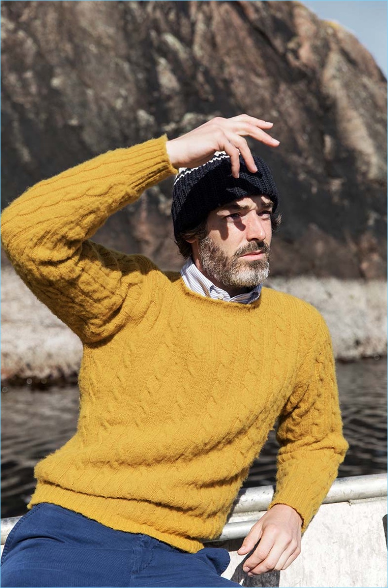 English model Richard Biedul wears a mustard yellow cable-knit sweater from Drake's.