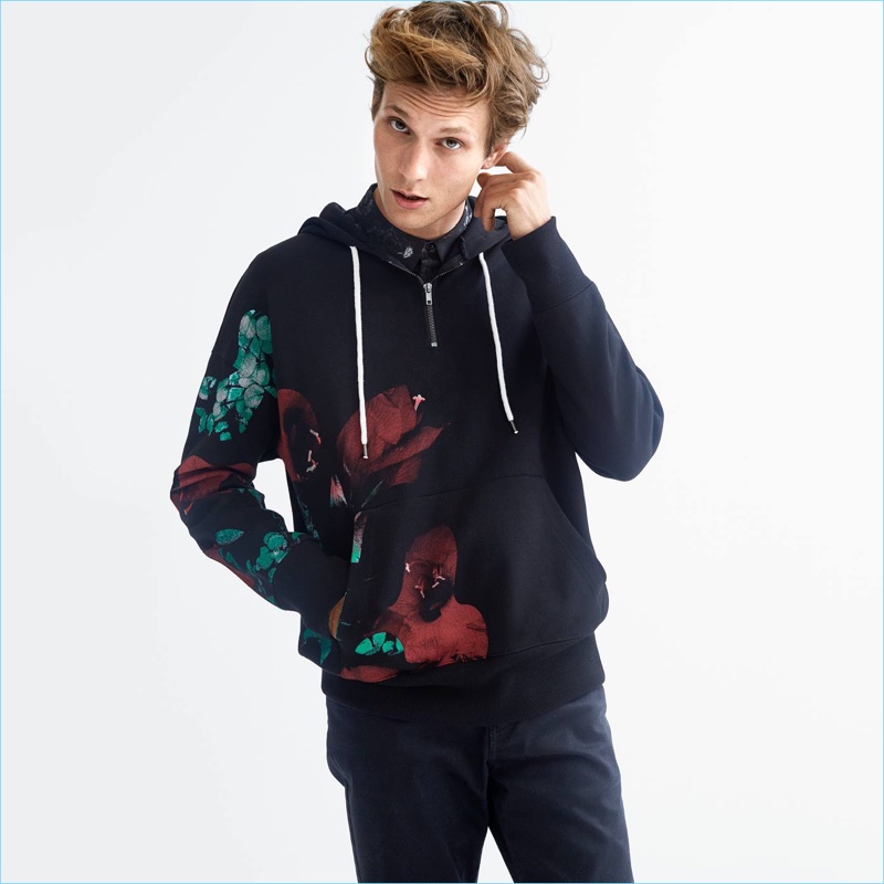 H&M makes a graphic statement with its hooded sweatshirt. Model Felix Gesnouin wears it with a patterned shirt and slim-fit pants.