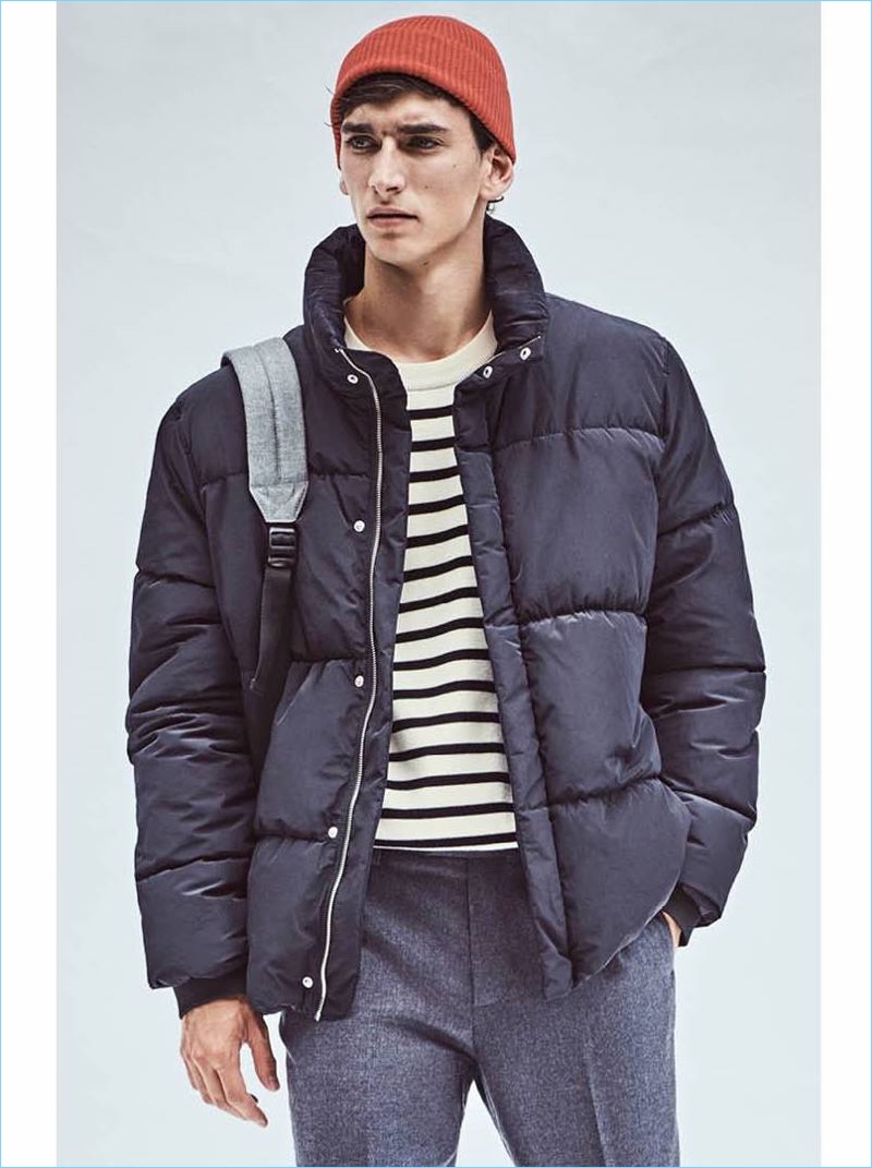 Stepping into casual style, Thibaud Charon wears a H&M padded jacket $79.99 and striped sweater $39.99. He also wears a red knit beanie $9.99 and suit pants $59.99.