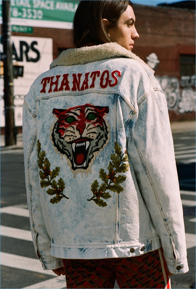 Model and music artist Ian Mellencamp wears a Gucci tiger-embroidered denim jacket with track pants.