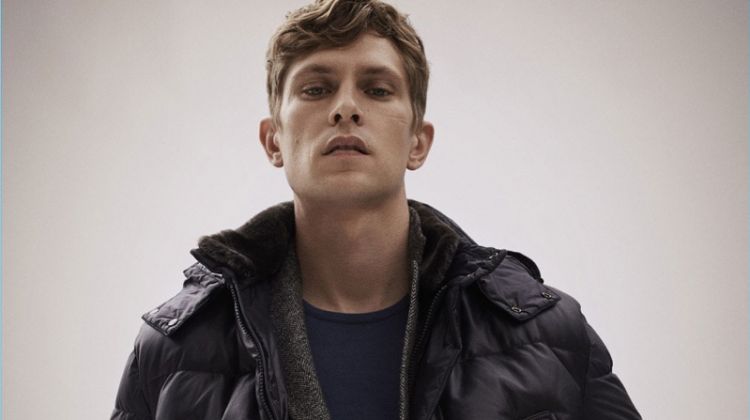 Layering for winter, Mathias Lauridsen wears a down jacket, herringbone suit, and sweater by Massimo Dutti.