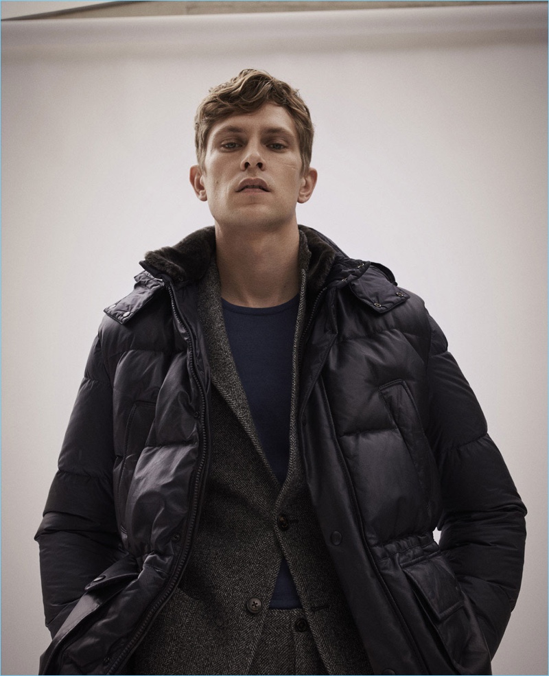 Layering for winter, Mathias Lauridsen wears a down jacket, herringbone suit, and sweater by Massimo Dutti.