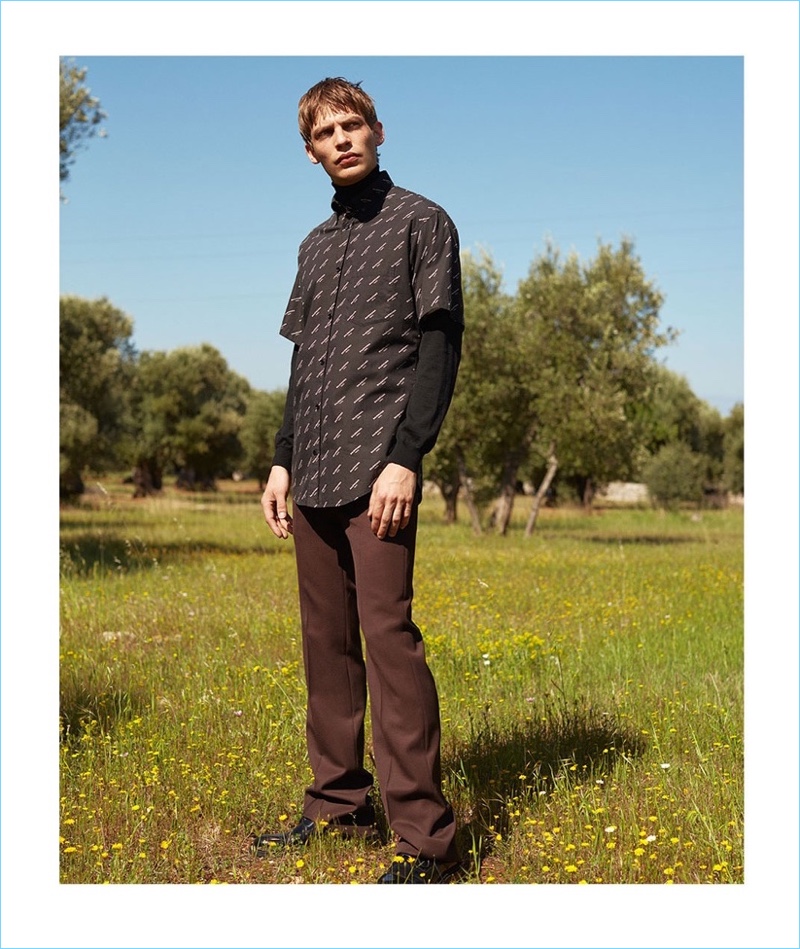 Baptiste Radufe wears a logo print short-sleeve shirt by Balenciaga with a Boglioli sweater. He also sports Valentino trousers and AMI shoes. 