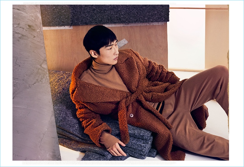 A cozy vision, Sang Woo Kim wears a coat, sweater, t-shirt, and track pants by Stella McCartney.