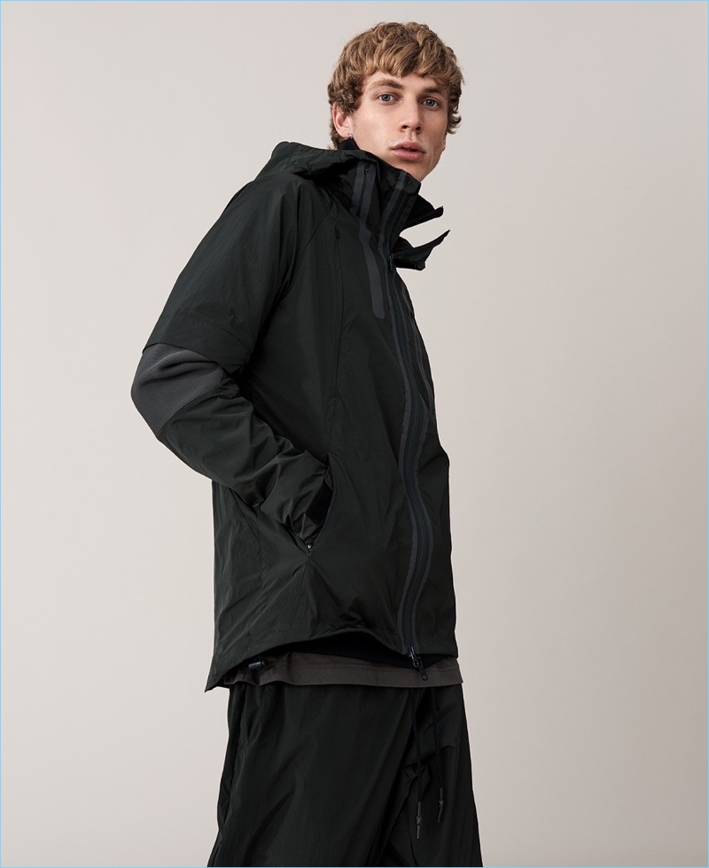 Dressed in black, Robbi G. sports a Y-3 quilted down jacket, logo t-shirt, and track pants.