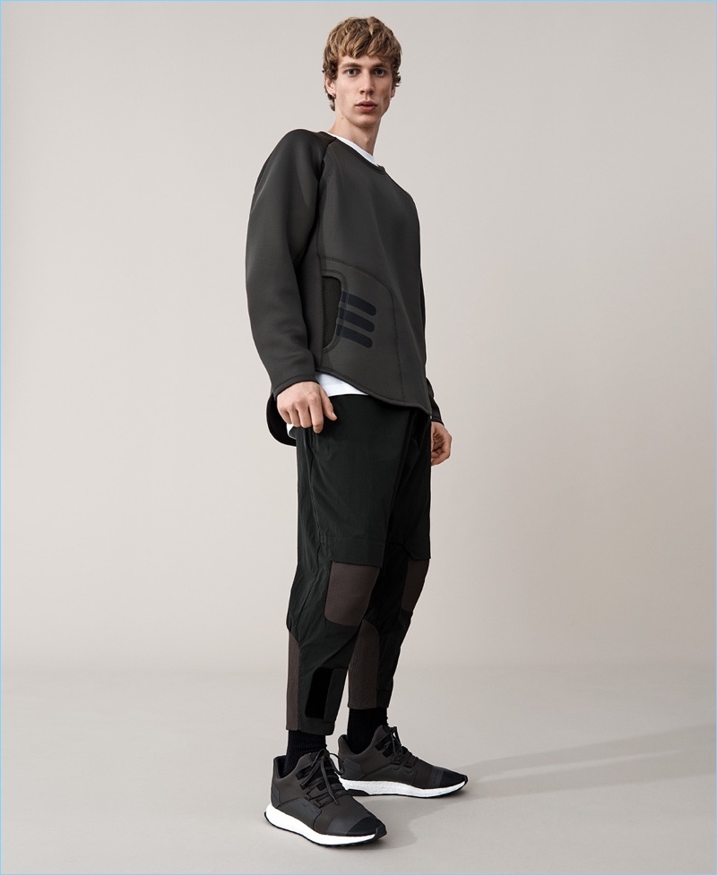 Embracing Yohji Yamamoto's modern proportions, Robbi G. wears a Y-3 neoprene sweatshirt and track pants. He also dons Y-3 sneakers and a logo t-shirt.