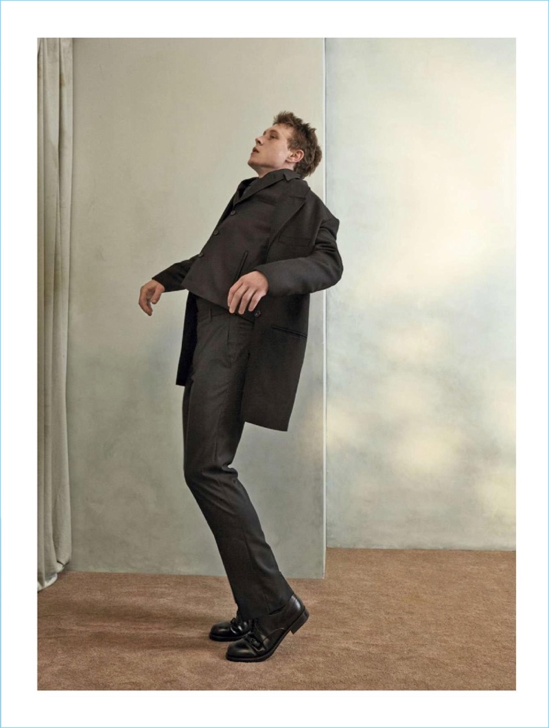 Appearing in a L’Officiel Hommes Italia photo shoot, George MacKay wears a Lemaire coat. MacKay also dons a Salvatore Ferragamo vest with a Giorgio Armani shirt and pants. A Canali tie and Bottega Veneta shoes complete MacKay’s look.