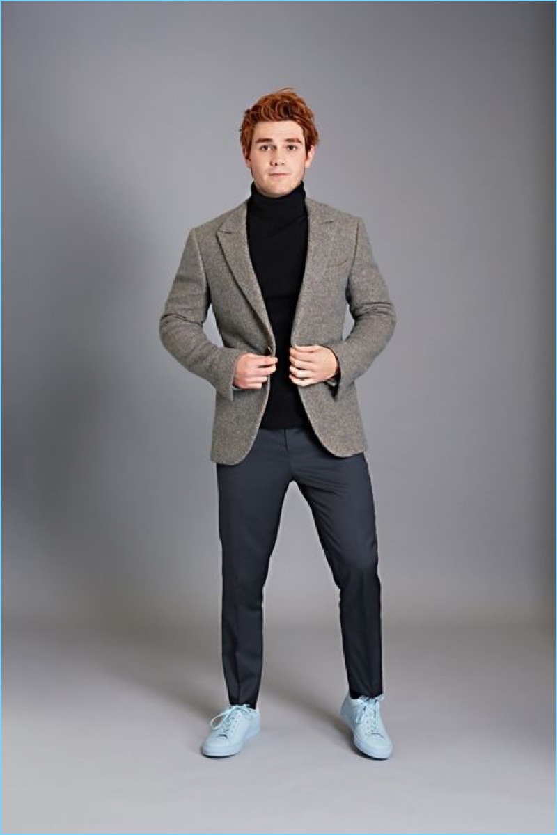KJ Apa wears an Ermenegildo Zegna Couture suit jacket with a Theory turtleneck sweater. Apa also sports Tommy Hilfiger trousers and Koio sneakers.
