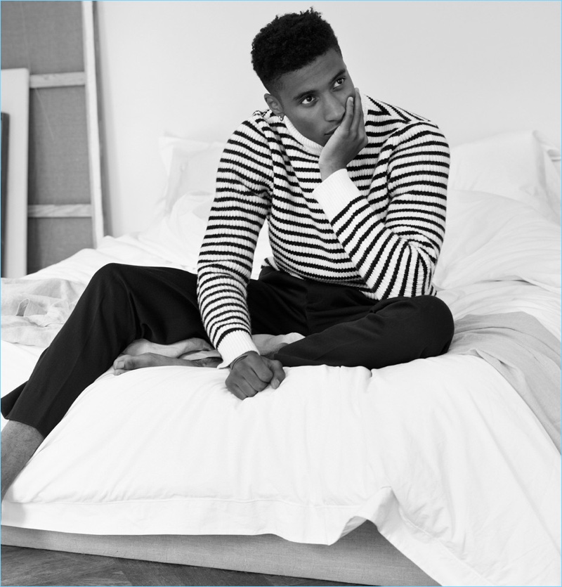 Relaxing, Joshua Payne wears a Mr P. striped turtleneck and wool trousers.