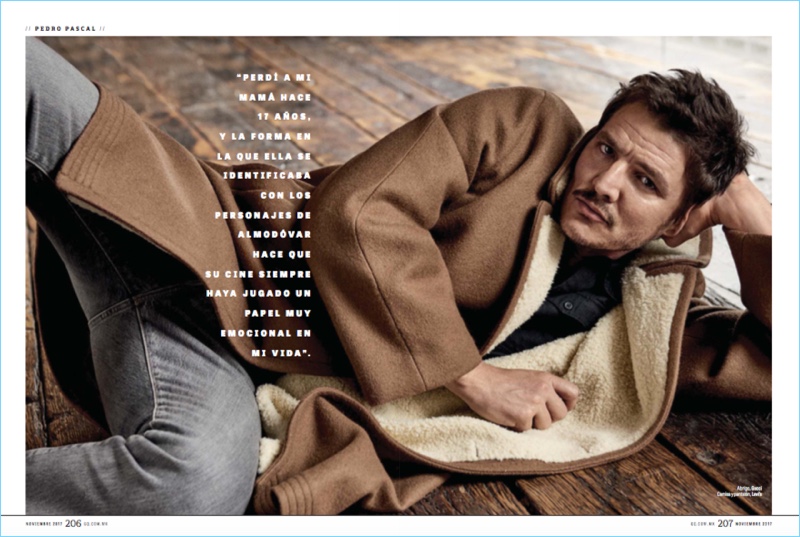 Laying down, Pedro Pascal wears a Gucci coat with a shirt and pants by Levi's.