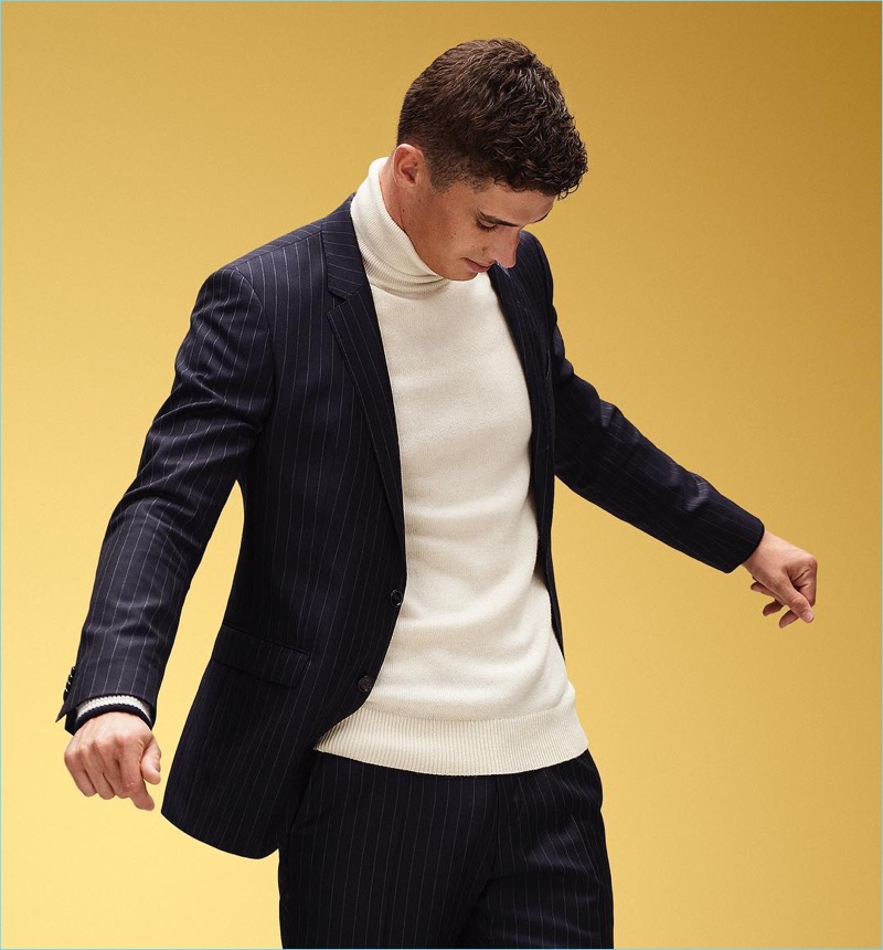 English model Matthew Holt sports a chic turtleneck and suit by Tommy Hilfiger.