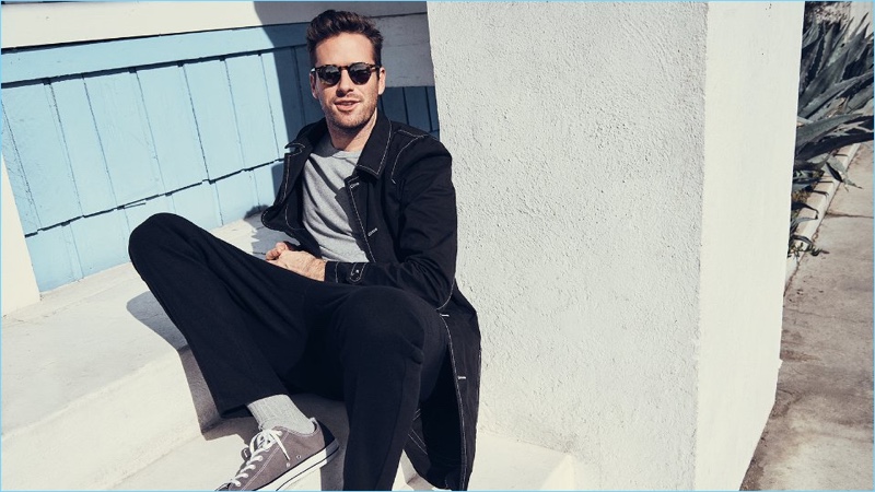 Relaxing, Armie Hammer wears a Comme des Garçons SHIRT jacket, Schiesser t-shirt, AMI trousers, Oliver Peoples sunglasses, and Converse sneakers.