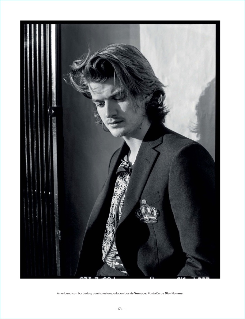 Appearing in a black and white photo, Joe Keery wears a Versace look with Dior Homme pants.