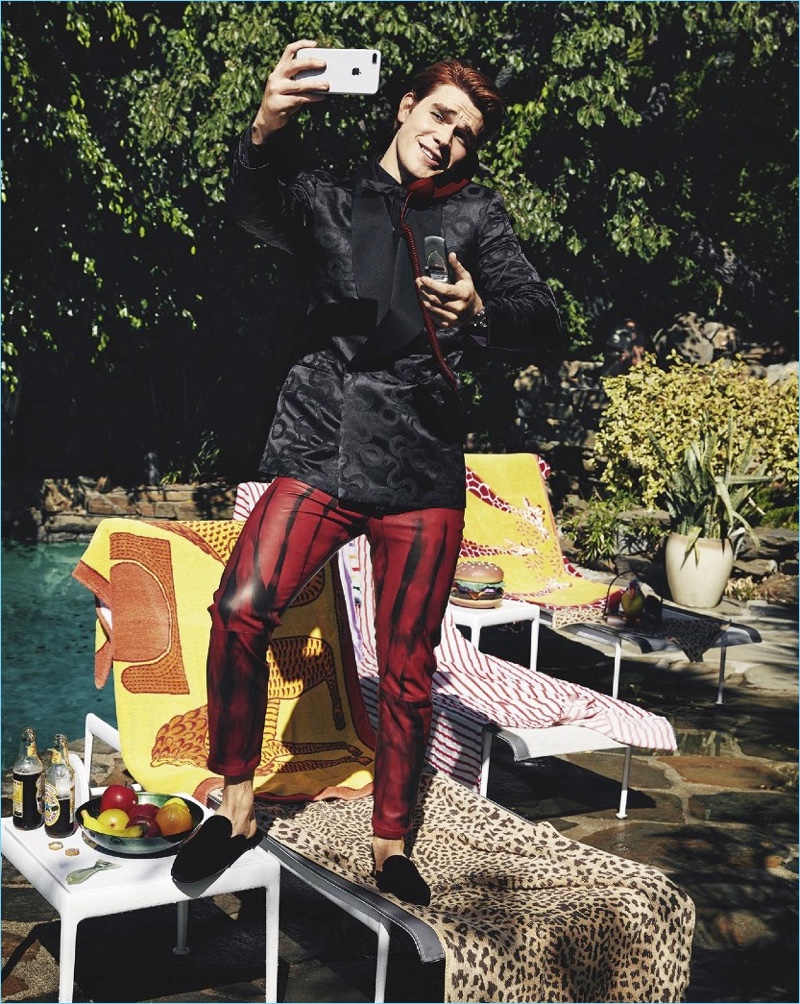 Posing for a selfie, KJ Apa sports a shirt, jacket, and bow-tie by Ralph Lauren Purple Label. He also wears Ann Demeulemeester pants and Dolce & Gabbana shoes.