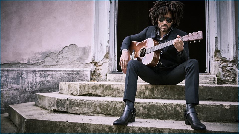 Playing the guitar, Lenny Kravitz wears a Saint Laurent tuxedo and boots with an Alexander McQueen shirt and Gucci sunglasses.