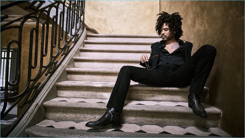 Relaxing, Lenny Kravitz wears a Saint Laurent blazer, trousers, and boots with a Haider Ackermann overshirt.