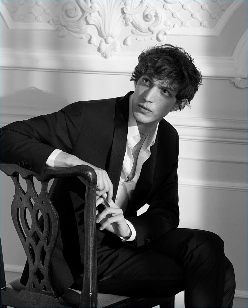 Sitting for a black and white portrait, Xavier Buestel dons a tuxedo by Valentino. The French model also sports a Dolce & Gabbana shirt and A.P.C. t-shirt.