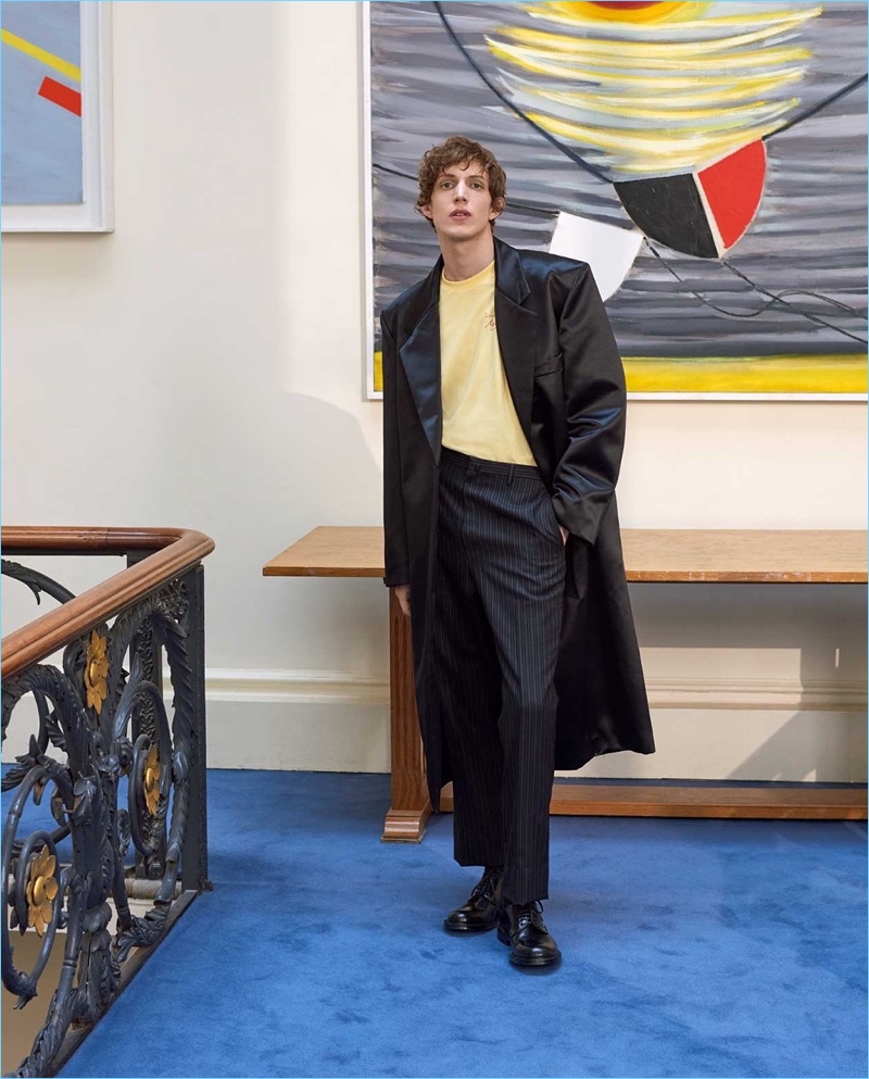 Embracing an artsy flair, Xavier Buestel wears a Raf Simons satin coat. He also sports a Marine Rose t-shirt, Lanvin trousers, and Prada shoes.