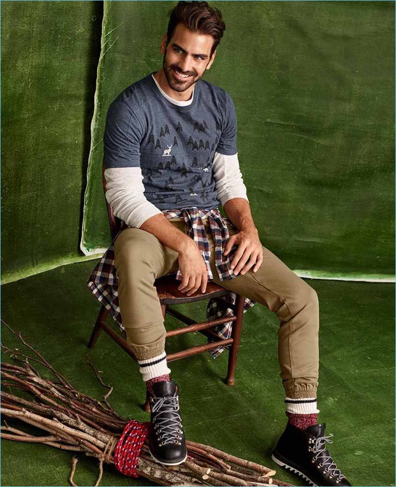 Delivering a charming smile, Nyle DiMarco sports a LE 31 t-shirt, Rumors chinos, and a Jachs Mfg Co. check shirt with Fracap x Simons boots.