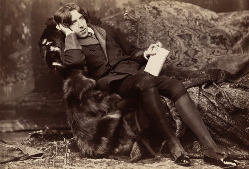Oscar Wilde wears an elegant smoking jacket.
