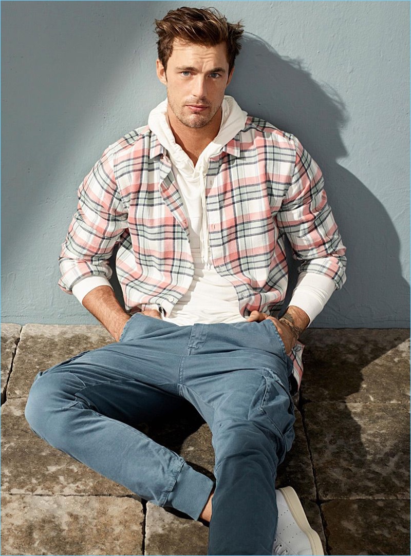 Christian Hogue wears a LE 31 pastel check shirt, hoodie, and Italian cargo joggers with Adidas x Pharrell Williams Stan Smith sneakers.