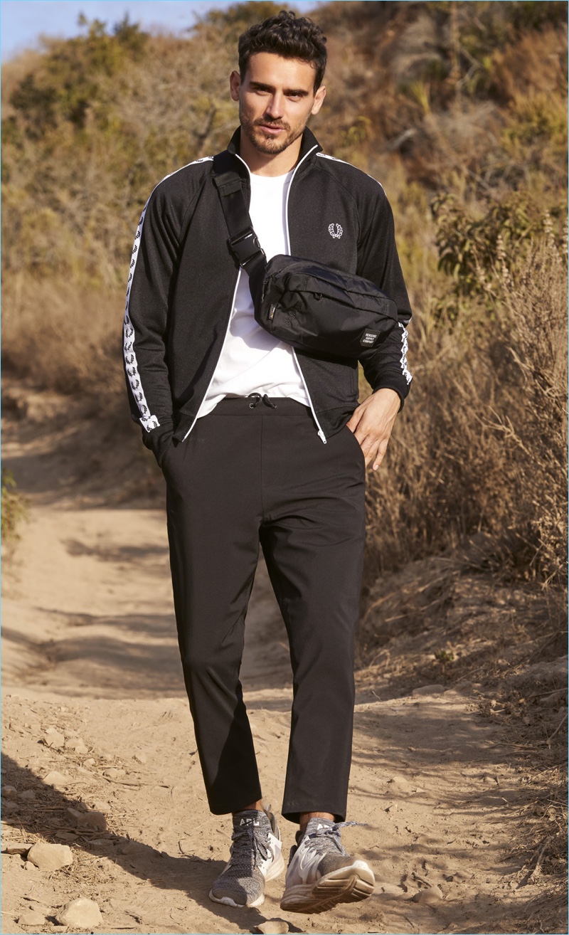 Going for a walk, Arthur Kulkov wears a Fred Perry track jacket with a Champion shirt, and DYNE pants. The top model also sports APL: Athletic Propulsion Labs sneakers and a Herschel Supply Co. hip pack.