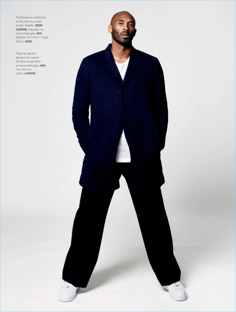 Standing tall, Kobe Bryant wears a t-shirt and cardigan by Dior Homme. The basketball star also sports AMI trousers and Nike Air Force 1 Triple white sneakers.