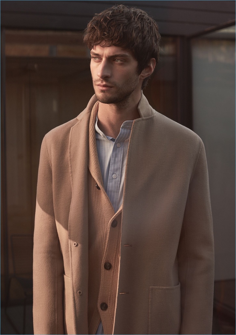 Layering neutrals, Matthew Bell sports a Reiss camel wool-blend overcoat and shawl-collar cardigan. He also wears a striped grandad collar shirt.