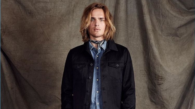Scotch & Soda proposes elevated double denim with its Amsterdams Blauw label. Here, Ton Heukels wears a black denim trucker jacket with a light wash denims shirt. Cropped trousers polish up the timeless look.