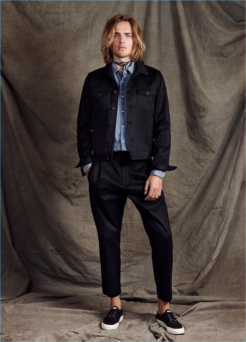 Scotch & Soda proposes elevated double denim with its Amsterdams Blauw label. Here, Ton Heukels wears a black denim trucker jacket with a light wash denims shirt. Cropped trousers polish up the timeless look.