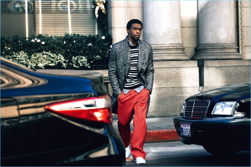 Going for a stroll, Chadwick Boseman wears a Mr P. herringbone coat and Saint Laurent fair isle sweater. He also sports a Freemans Sporting Club shirt, Maison Margiela trousers, and Saint Laurent sneakers.