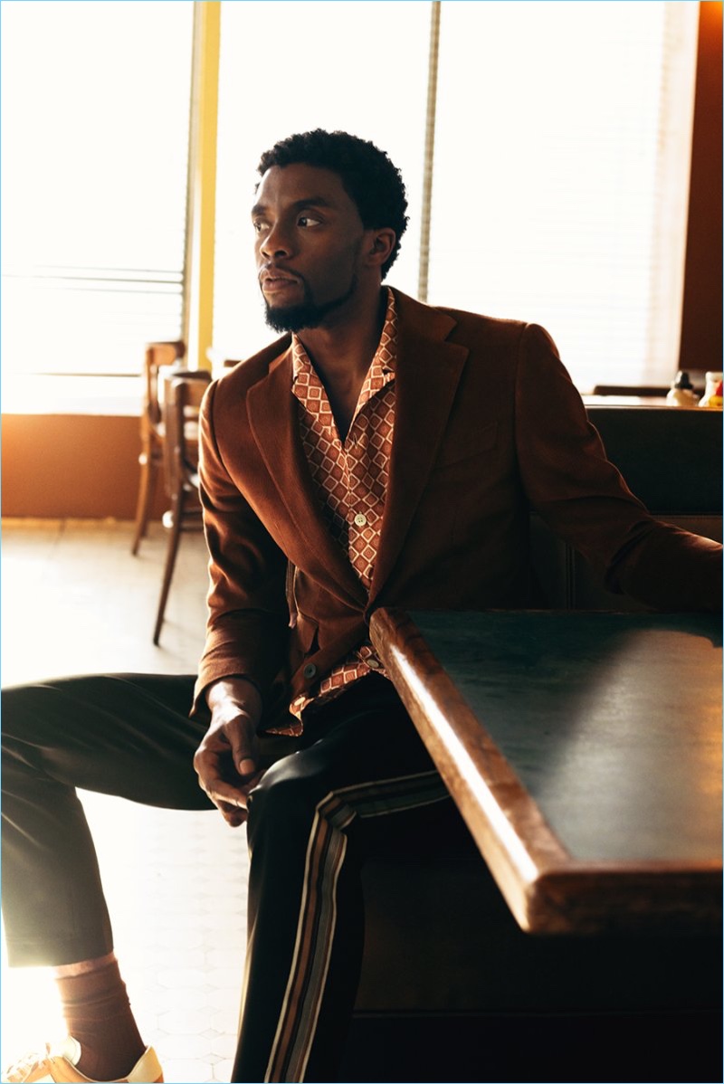 Actor Chadwick Boseman sports a Thom Sweeney corduroy suit jacket and Prada shirt. Boseman also wears CMMN SWDN satin sweatpants and Paul Smith sneakers.